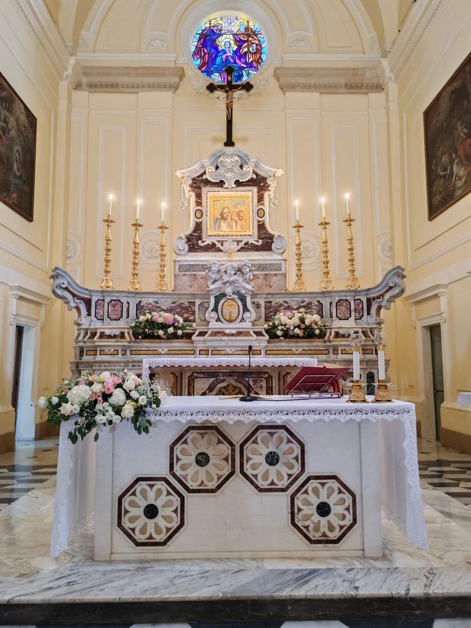 Altare di chiesa addobbato con composizioni di rose bianche e rosa, gypsophila e verde sulla mensa e sulla balaustra