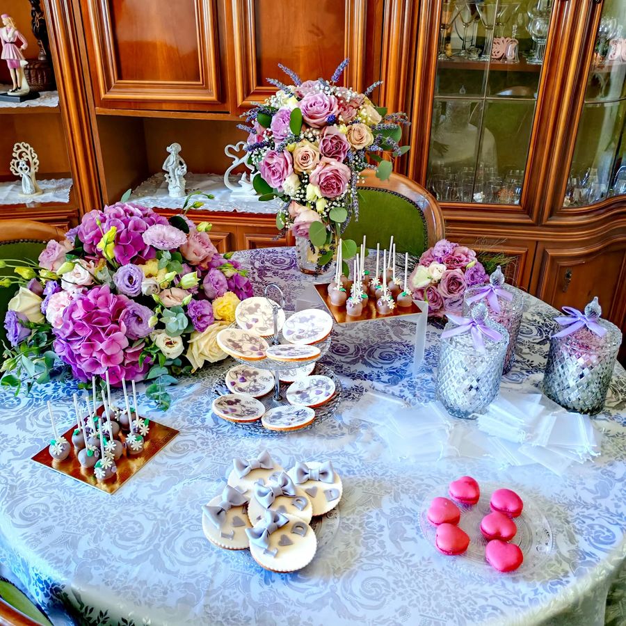 Tavolo della confettata sui toni del lilla con bouquet a cascata, cake pops, biscotti decorati, macarons e bomboniere in vetro