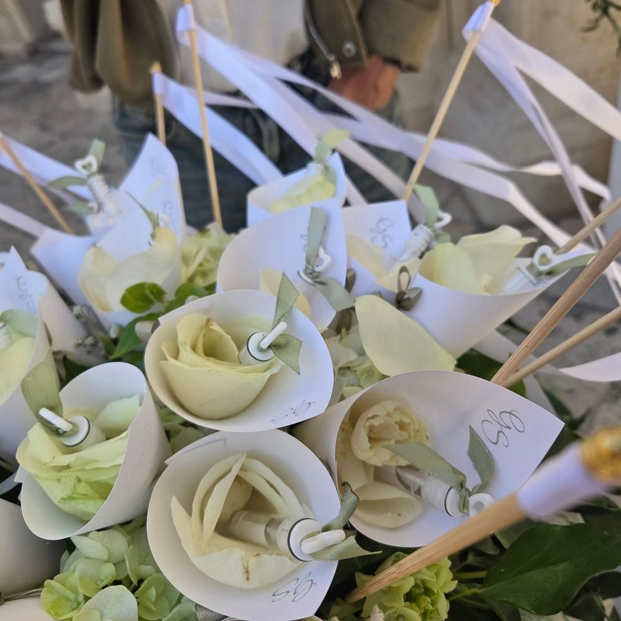 Coni di carta con rosa bianca singola, nastri di raso e bacchette con nastri per il lancio agli sposi